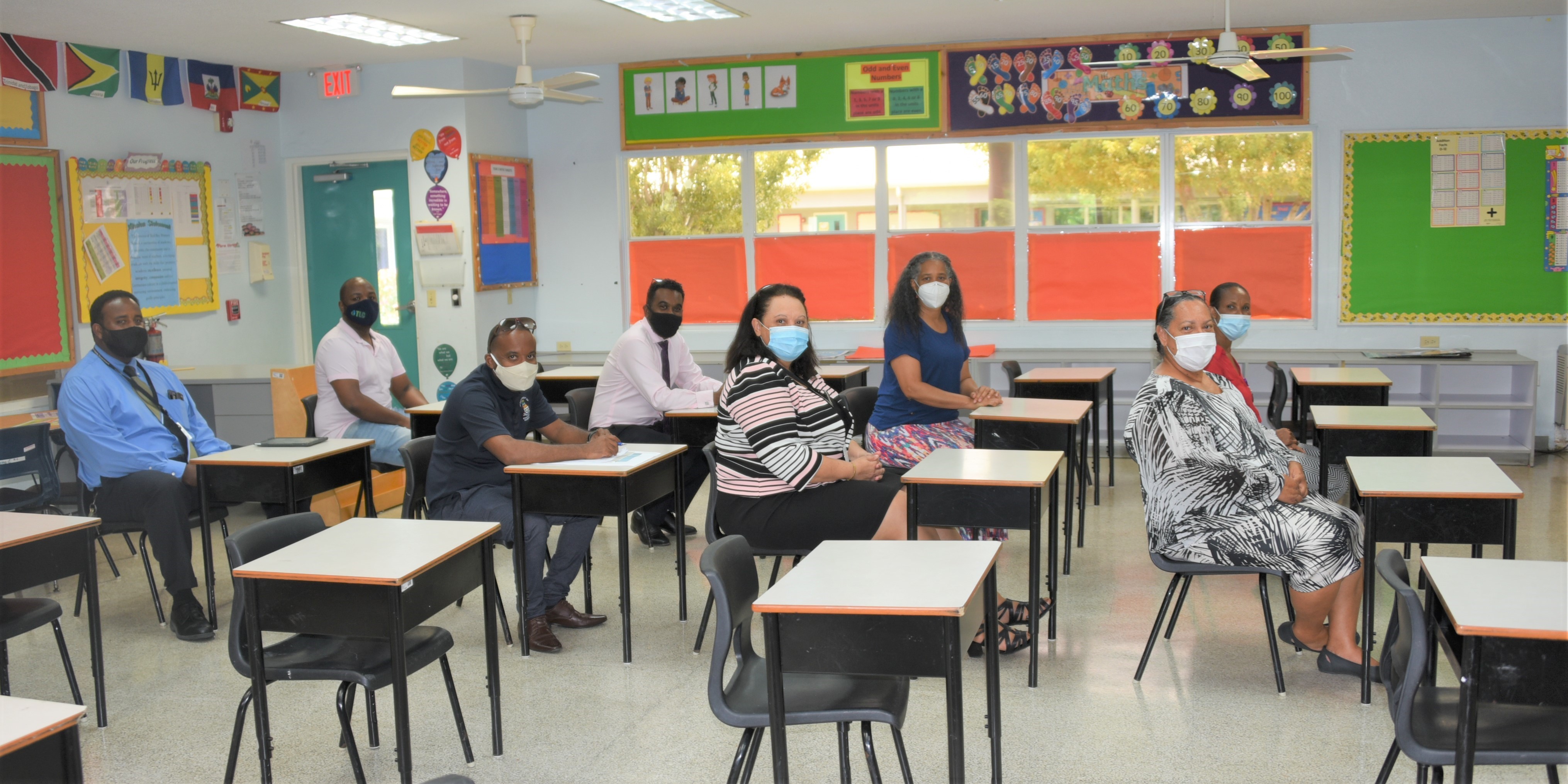 The team headed by Minister Juliana O’Connor-Connolly (front) demonstrate sitting 3 ft apart in a classroom at the Red Bay Primary School