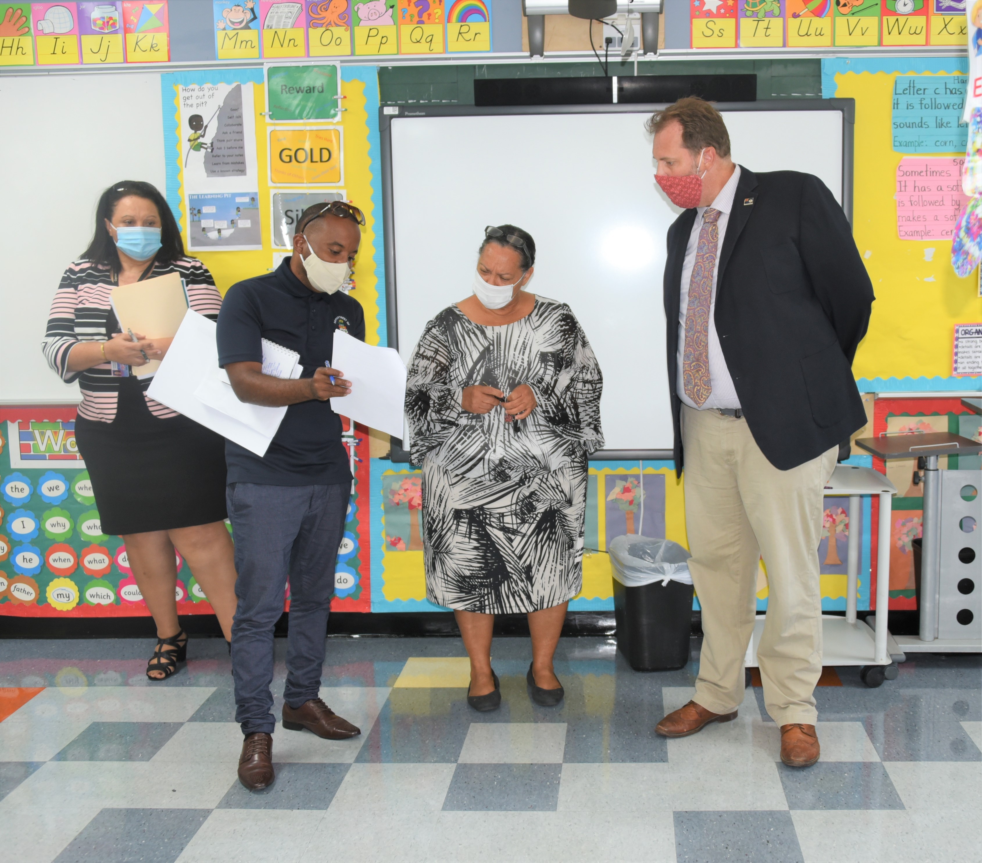 DES Acting Facilities Manager Glen Arek Gardner (l) shows DES Acting Director Tammy Banks-DaCosta (background), Minister Juliana O’Connor-Connolly (centre) and Prospect Primary School Principal Matthew Read (r) some of the proposed plans for the school’s reopening.